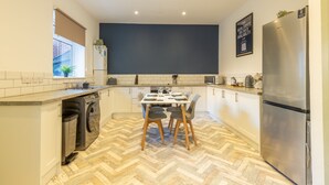 A modern kitchen with a dining table, chairs, a built-in washing machine, and a refrigerator. - Anika in South Shields (South Shields)