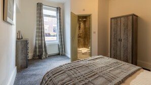 A bedroom with a bed, a wardrobe, a shower room, and a window with curtains. - Anika in South Shields (South Shields)
