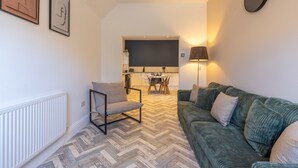 A living room with a sofa, a chair, a dining table, and a kitchen in the background. - Anika in South Shields (South Shields)