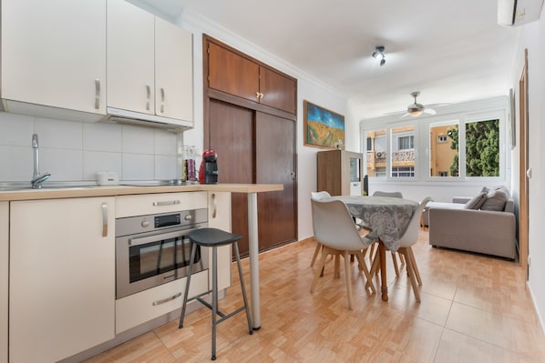 A modern kitchen with a built-in oven, a coffee machine, and a dining area with a table and chairs.