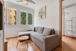 A modern living room with a grey sectional sofa, a small round table, and a ceiling fan.