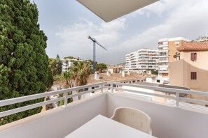 A balcony with a view of a construction crane, buildings, and trees.