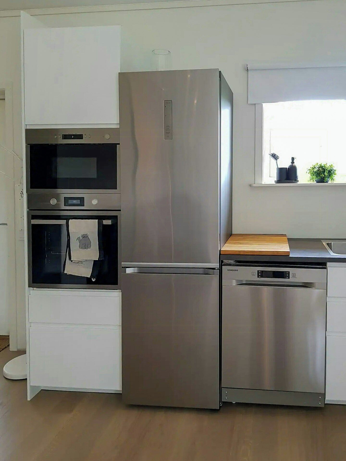 Una cocina con refrigerador, horno y lavavajillas de acero inoxidable.