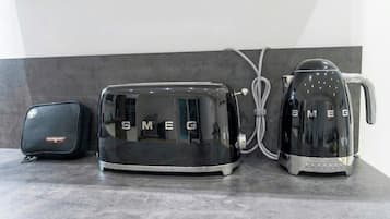 Una cocina con un tostador negro, un hervidor y un aparato Housegard negro sobre una encimera gris.