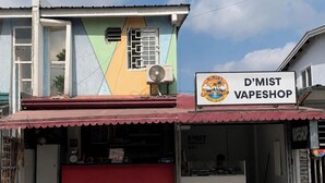 A two-story building with a red awning and a sign for 'D'MIST VAPESHOP' on the ground floor.