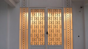 Un conjunto de puertas dobles con detalles metálicos intrincados y una cálida fuente de luz detrás.