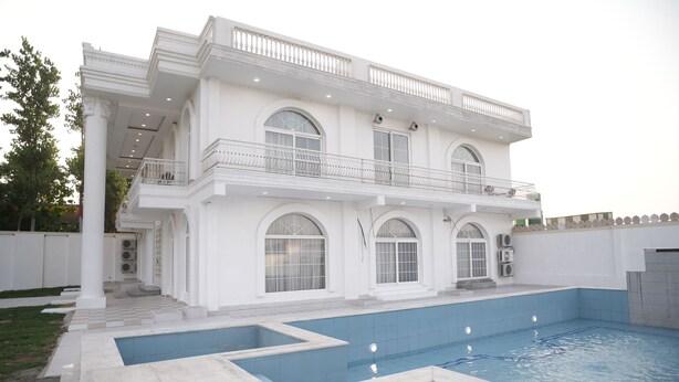 Un edificio de dos pisos con piscina, ventanas amplias y un balcón.