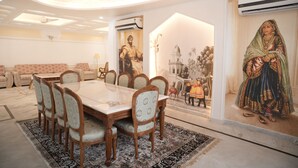 Un comedor con una mesa grande y sillas, un tapete estampado y un mural en la pared.
