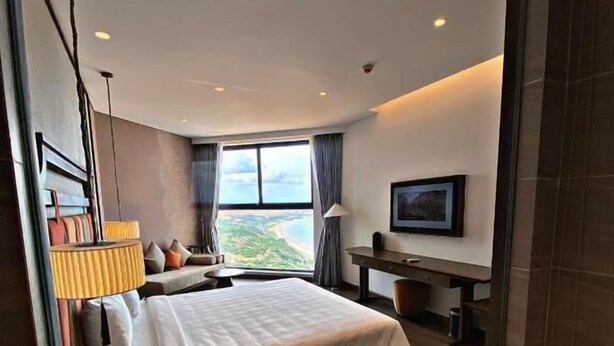 Habitación de hotel moderna con una cama grande, un escritorio y vistas a la ciudad.