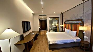Habitación de hotel con cama, mesita de noche, lámpara y televisor montado en la pared.
