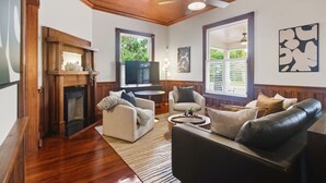 Un salon doté d’une cheminée, d’un ventilateur de plafond et d’une grande fenêtre.