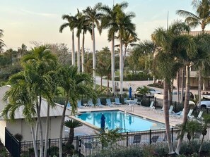 A swimming pool surrounded by palm trees and lounge chairs. - Sanibel Sunrise 3 bed 3 bath Beachfront Condo (Sanibel)