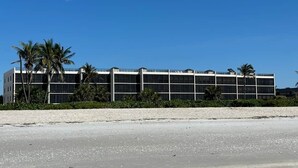 Ein modernes Gebäude mit flachem Dach, großen Fenstern und einem sandigen Strand im Vordergrund.