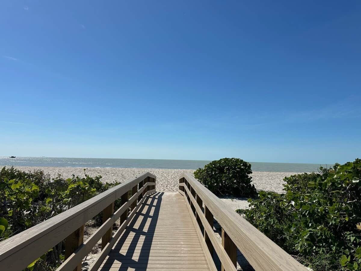 A wooden boardwalk leading to a beach with clear skies.