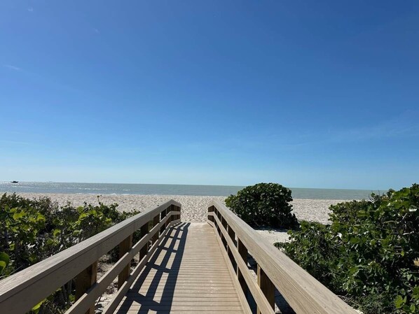 A wooden boardwalk leading to a beach with clear skies. - Sanibel Sunrise 3 bed 3 bath Beachfront Condo (Sanibel)