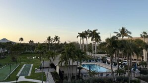 Ein Resort mit Schwimmbad, Palmen und Tennisplatz.
