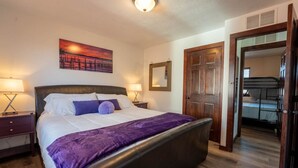 Una camera da letto con un letto, due comodini, un tavolino e una porta che dà su un corridoio.
