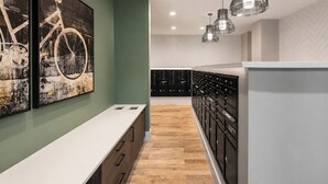 A modern kitchen with wooden cabinets, a white countertop, and a bicycle-themed artwork on the wall.