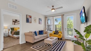 A living room with a beige sofa, a yellow armchair, a coffee table, and a ceiling fan.