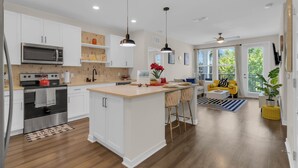 A modern kitchen with white cabinetry, stainless steel appliances, and a central island.