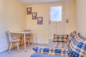 A small room with a sofa, a table, and a chair. There are three framed pictures on the wall.