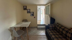 Um quarto com uma mesa de jantar, um sofá e uma porta que dá para uma área externa.