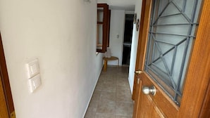 Um corredor com uma porta de madeira, uma pequena mesa e um interruptor de luz na parede.