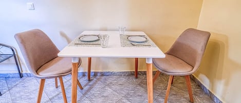 A dining table with two chairs, a tiled floor, and a small rug.