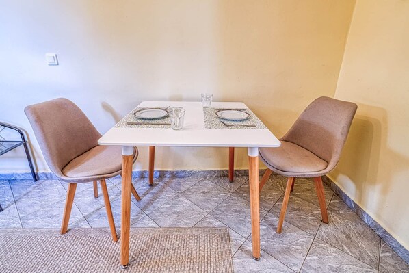 A dining table with two chairs, a tiled floor, and a small rug.