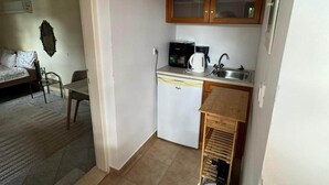 Uma cozinha compacta com geladeira, cafeteira e pia.