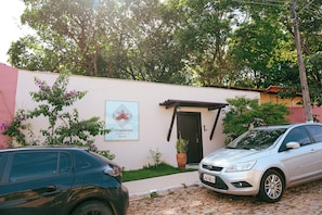 Um edifício com uma placa indicando 'Templários ECOVILLA Pousada', um caminho de acesso pavimentado e dois carros estacionados.