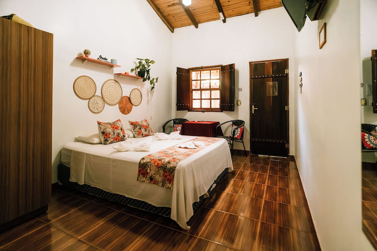 Um quarto com cama, cadeira, janela e porta.
