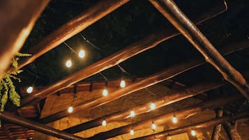 Une structure en bois au plafond, agrémentée de suspensions lumineuses et de fougères.