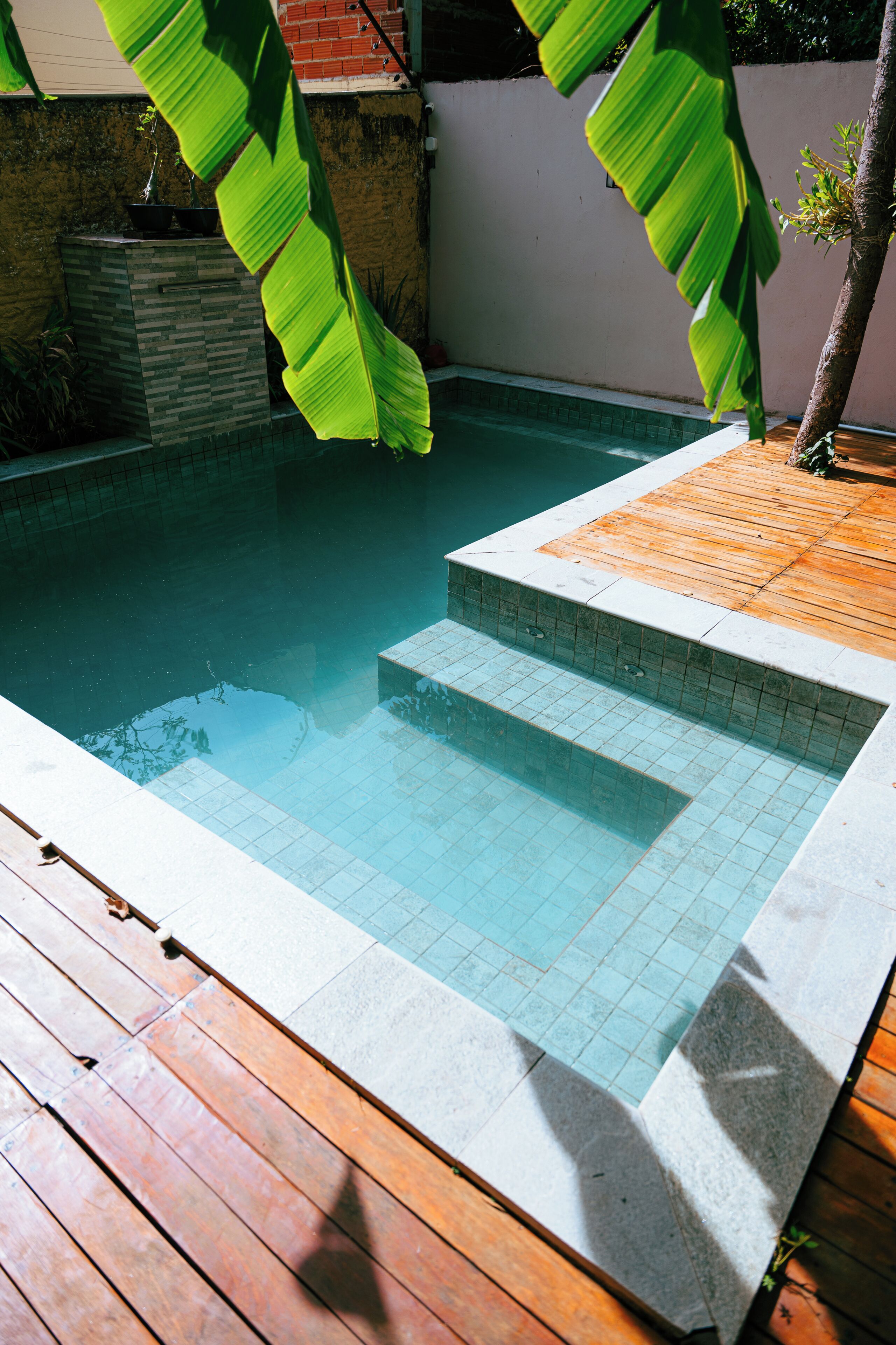 Una piscina con cubierta de madera y escalones de cerámica para entrar.