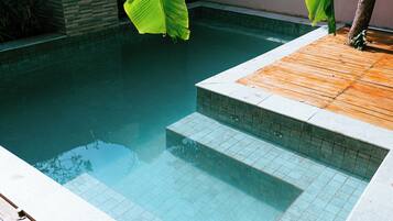Una piscina con cubierta de madera y escalones de cerámica para entrar.