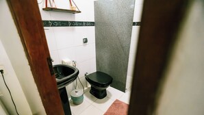 A bathroom with a toilet, sink, and a trash bin. - Pousada Templários Ecovilla  (Pirenópolis)