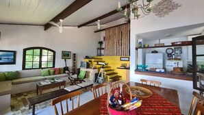A spacious living area with a sofa, dining table, and a staircase leading to an upper level.