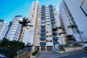 A multi-story residential building with balconies, a gated entrance, and a staircase leading to the entrance.