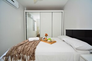 Hotelkamer met een bed, nachtkastje, dienblad met ontbijtartikelen, spiegel en een kledingkast.