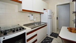 Una cocina compacta equipada con estufa a gas, pileta, refrigerador y microondas.