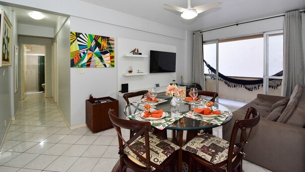 Un comedor con una mesa redonda, sillas y un televisor en la pared.