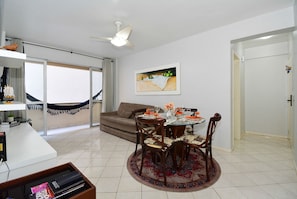A dining area with a round table, chairs, a ceiling fan, and a large window with a view.