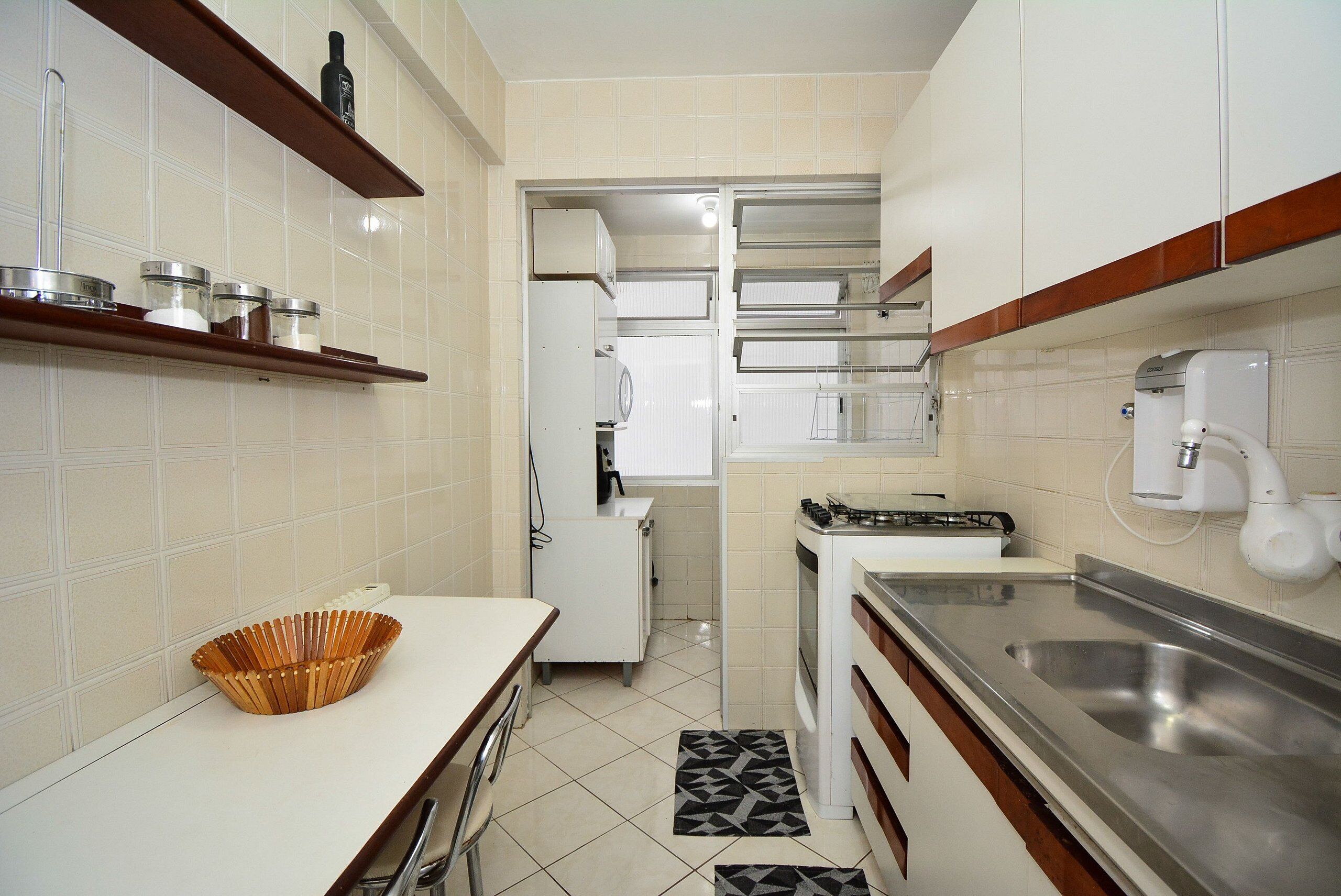 Una cocina con gabinetes blancos, un fregadero de acero inoxidable y un microondas.