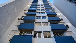 Un edificio de varios pisos con balcones, equipos de aire acondicionado y ventanas.