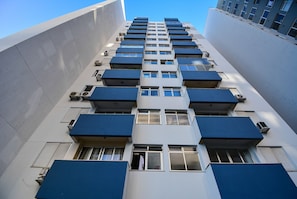 Un edificio de varios pisos con balcones, equipos de aire acondicionado y ventanas.