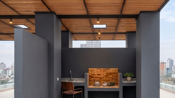 A modern outdoor kitchen with a wooden ceiling, a built-in bench, and a view of the cityscape. - Barrio París Londres - Domus Travels (Santiago)