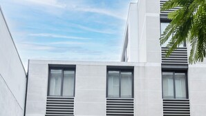 A modern building with a flat facade, large windows, and a visible entrance with a sign reading 'ALTURA MAXIMA 2.10 mts'. - Barrio París Londres - Domus Travels (Santiago)