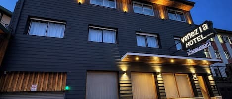 Ett modernt hotell med en mörk fasad, många fönster och en skylt som visar att det är ett hotell.
