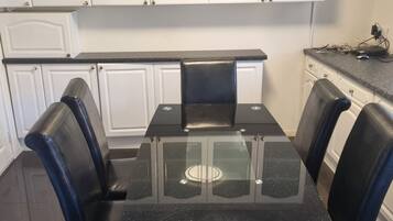 A kitchen with a black glass-top table and four black chairs.