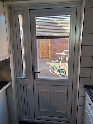 A door with a window, a wooden door in the background, and a bicycle outside.